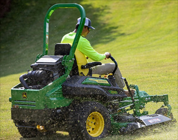 worker mowing lawn with a profesional mower